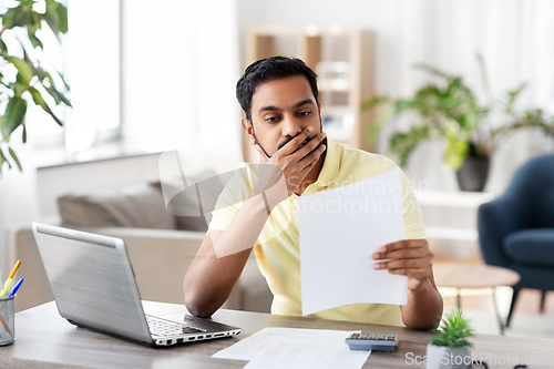 Image of man with calculator and papers working at home