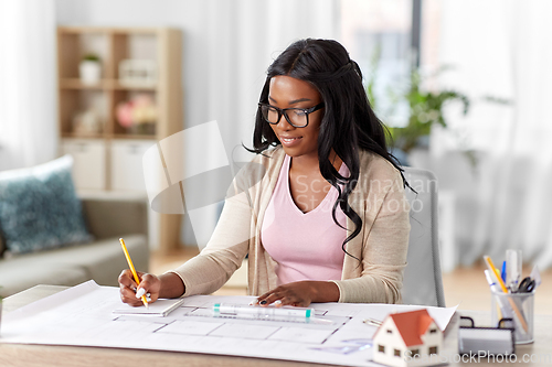 Image of female architect with house model and blueprint