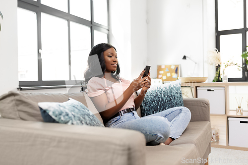 Image of african american woman with smartphone at home