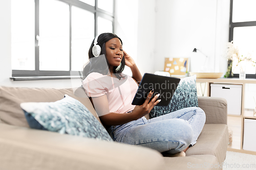 Image of woman with tablet pc listening to music at home