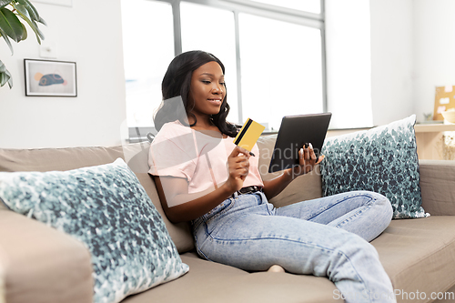 Image of happy woman with tablet pc and credit card at home