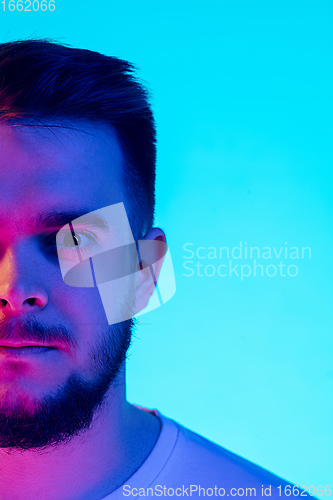 Image of Caucasian man\'s portrait isolated on blue studio background in neon light. Concept of human emotions, facial expression, sales, ad.