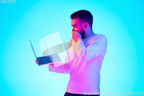 Image of Caucasian man\'s portrait isolated on blue studio background in neon light. Concept of human emotions, facial expression, sales, ad.