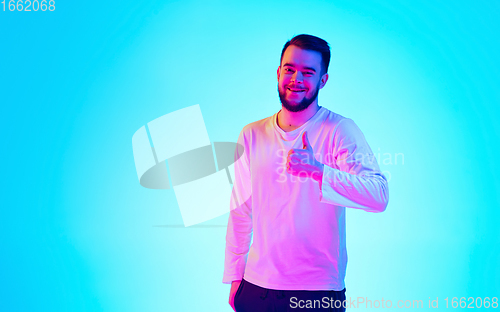 Image of Caucasian man\'s portrait isolated on blue studio background in neon light. Concept of human emotions, facial expression, sales, ad.