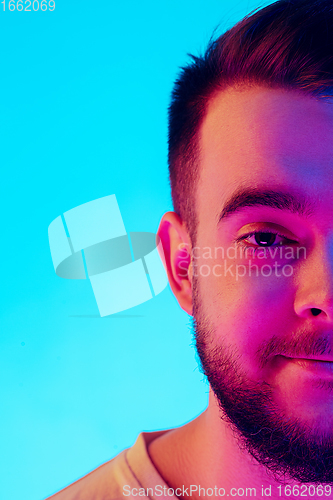 Image of Caucasian man\'s portrait isolated on blue studio background in neon light. Concept of human emotions, facial expression, sales, ad.