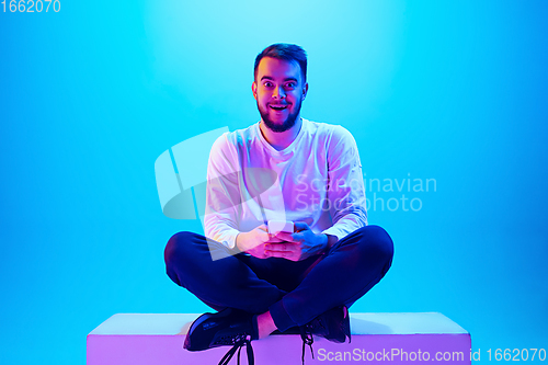 Image of Caucasian man\'s portrait isolated on blue studio background in neon light. Concept of human emotions, facial expression, sales, ad.