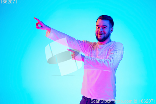 Image of Caucasian man\'s portrait isolated on blue studio background in neon light. Concept of human emotions, facial expression, sales, ad.