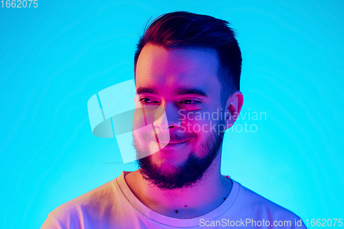 Image of Caucasian man\'s portrait isolated on blue studio background in neon light. Concept of human emotions, facial expression, sales, ad.