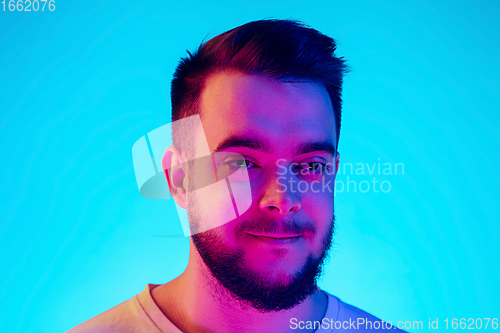 Image of Caucasian man\'s portrait isolated on blue studio background in neon light. Concept of human emotions, facial expression, sales, ad.