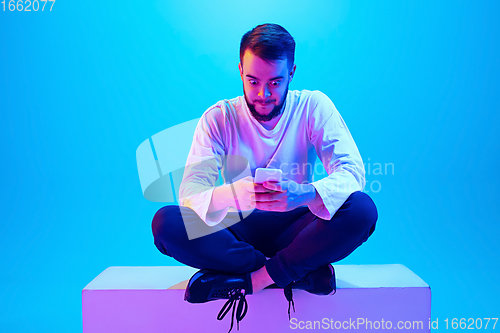 Image of Caucasian man\'s portrait isolated on blue studio background in neon light. Concept of human emotions, facial expression, sales, ad.