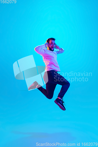 Image of Caucasian man\'s portrait isolated on blue studio background in neon light. Concept of human emotions, facial expression, sales, ad.