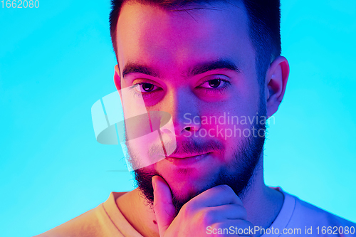 Image of Caucasian man\'s portrait isolated on blue studio background in neon light. Concept of human emotions, facial expression, sales, ad.