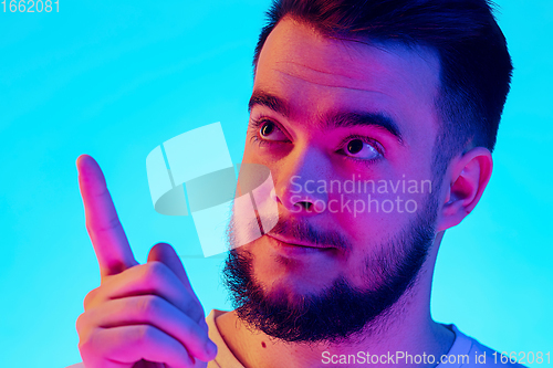 Image of Caucasian man\'s portrait isolated on blue studio background in neon light. Concept of human emotions, facial expression, sales, ad.