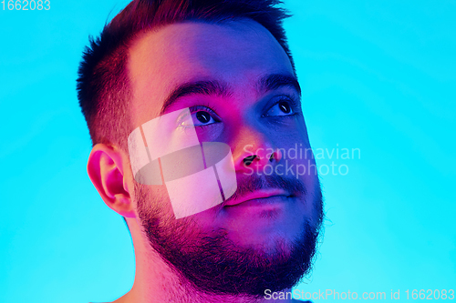 Image of Caucasian man\'s portrait isolated on blue studio background in neon light. Concept of human emotions, facial expression, sales, ad.