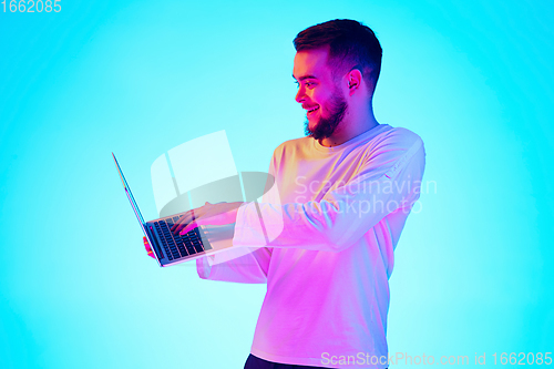 Image of Caucasian man\'s portrait isolated on blue studio background in neon light. Concept of human emotions, facial expression, sales, ad.