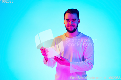 Image of Caucasian man\'s portrait isolated on blue studio background in neon light. Concept of human emotions, facial expression, sales, ad.