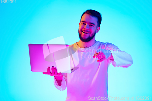 Image of Caucasian man\'s portrait isolated on blue studio background in neon light. Concept of human emotions, facial expression, sales, ad.