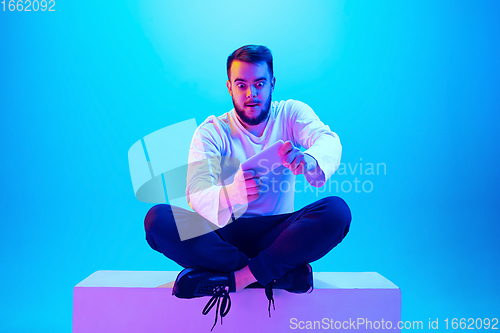 Image of Caucasian man\'s portrait isolated on blue studio background in neon light. Concept of human emotions, facial expression, sales, ad.