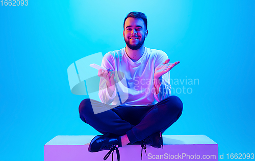 Image of Caucasian man\'s portrait isolated on blue studio background in neon light. Concept of human emotions, facial expression, sales, ad.