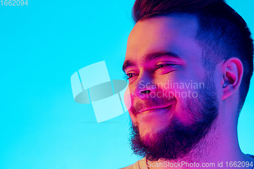 Image of Caucasian man\'s portrait isolated on blue studio background in neon light. Concept of human emotions, facial expression, sales, ad.