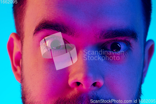 Image of Caucasian man\'s portrait isolated on blue studio background in neon light. Concept of human emotions, facial expression, sales, ad.