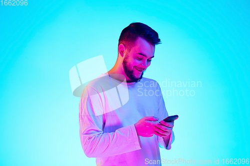 Image of Caucasian man\'s portrait isolated on blue studio background in neon light. Concept of human emotions, facial expression, sales, ad.