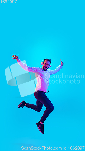 Image of Caucasian man\'s portrait isolated on blue studio background in neon light. Concept of human emotions, facial expression, sales, ad.