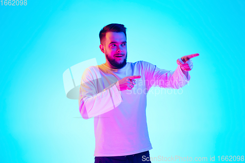 Image of Caucasian man\'s portrait isolated on blue studio background in neon light. Concept of human emotions, facial expression, sales, ad.