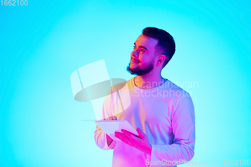 Image of Caucasian man\'s portrait isolated on blue studio background in neon light. Concept of human emotions, facial expression, sales, ad.