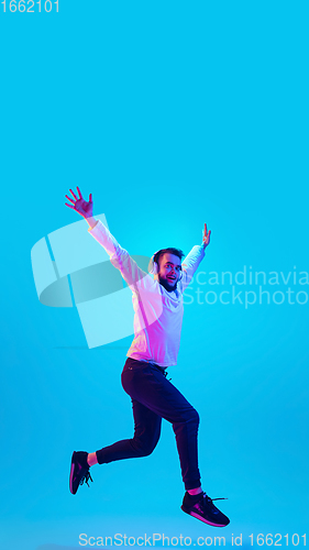 Image of Caucasian man\'s portrait isolated on blue studio background in neon light. Concept of human emotions, facial expression, sales, ad.