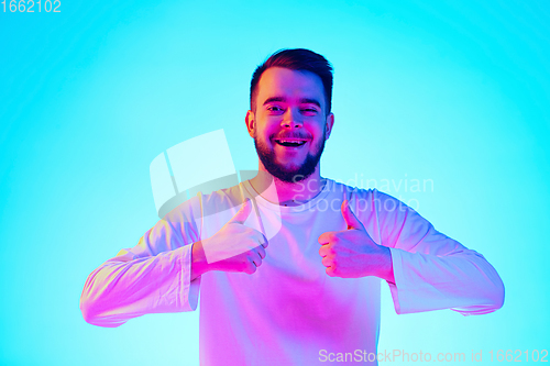 Image of Caucasian man\'s portrait isolated on blue studio background in neon light. Concept of human emotions, facial expression, sales, ad.