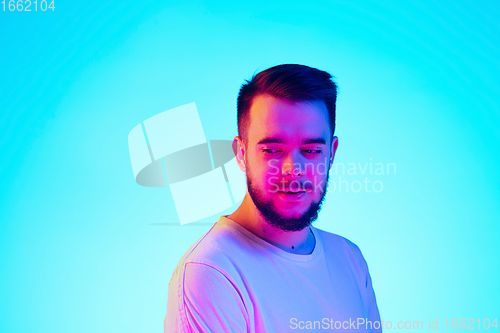 Image of Caucasian man\'s portrait isolated on blue studio background in neon light. Concept of human emotions, facial expression, sales, ad.