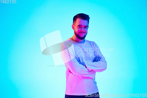 Image of Caucasian man\'s portrait isolated on blue studio background in neon light. Concept of human emotions, facial expression, sales, ad.