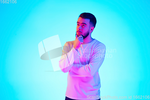 Image of Caucasian man\'s portrait isolated on blue studio background in neon light. Concept of human emotions, facial expression, sales, ad.