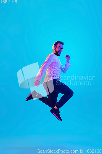 Image of Caucasian man\'s portrait isolated on blue studio background in neon light. Concept of human emotions, facial expression, sales, ad.