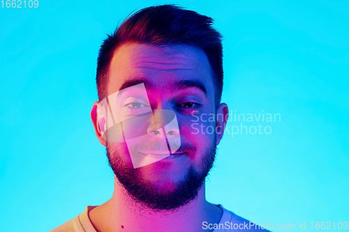 Image of Caucasian man\'s portrait isolated on blue studio background in neon light. Concept of human emotions, facial expression, sales, ad.