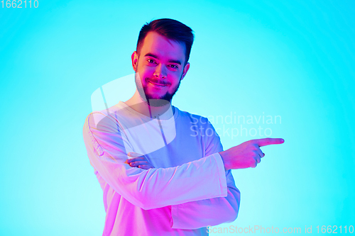 Image of Caucasian man\'s portrait isolated on blue studio background in neon light. Concept of human emotions, facial expression, sales, ad.