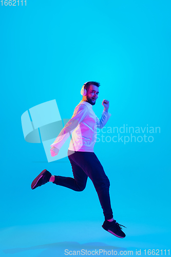 Image of Caucasian man\'s portrait isolated on blue studio background in neon light. Concept of human emotions, facial expression, sales, ad.