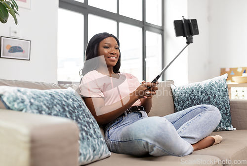 Image of happy african american woman taking selfie at home