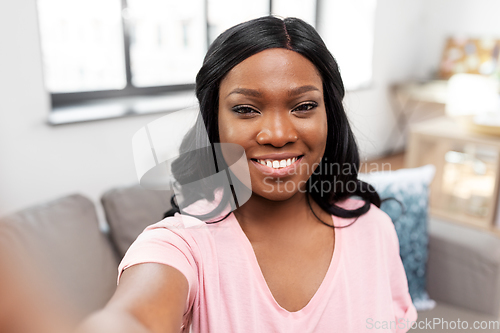 Image of happy african american woman taking selfie at home