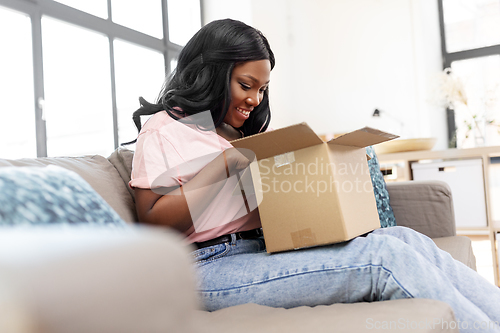 Image of african american woman opening parcel box at home