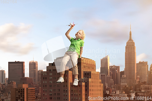 Image of See the world by children\'s eyes - little cute curly boy playing with airplane sitting on the business centre