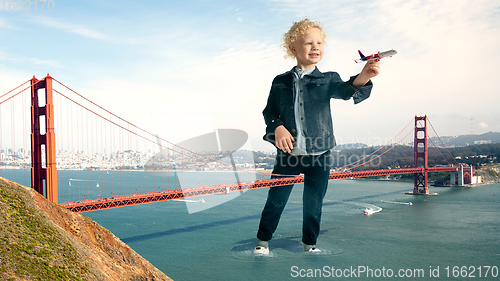 Image of See the world by children\'s eyes - little cute curly boy playing with airplane standing on the bridge