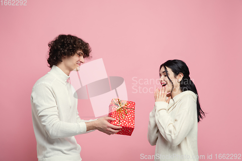 Image of Young, beautiful couple in love on pink studio background. Valentine\'s Day, love and emotions concept