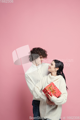 Image of Young, beautiful couple in love on pink studio background. Valentine\'s Day, love and emotions concept