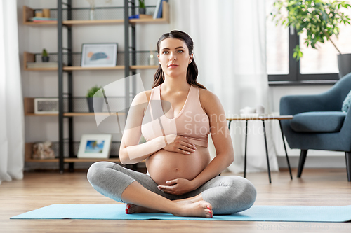 Image of happy pregnant woman doing yoga at home