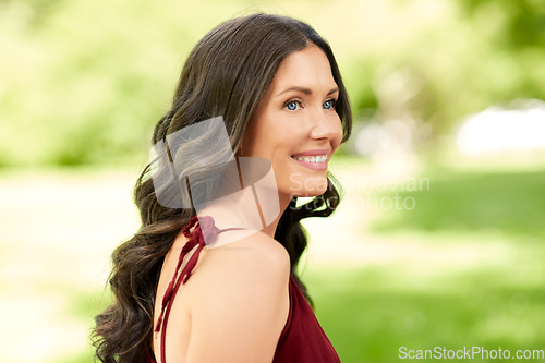 Image of portrait of happy smiling woman at summer park