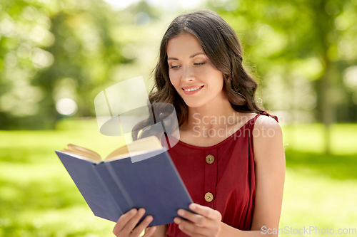 Image of happy smiling woman reading book at park