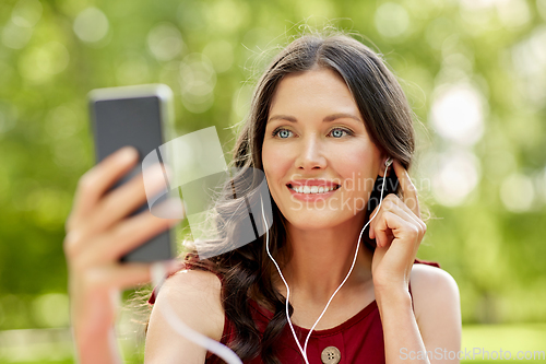 Image of woman with smartphone and earphones at park