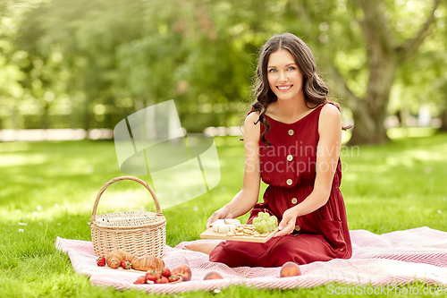 Image of happy woman with food and picnic basket at park